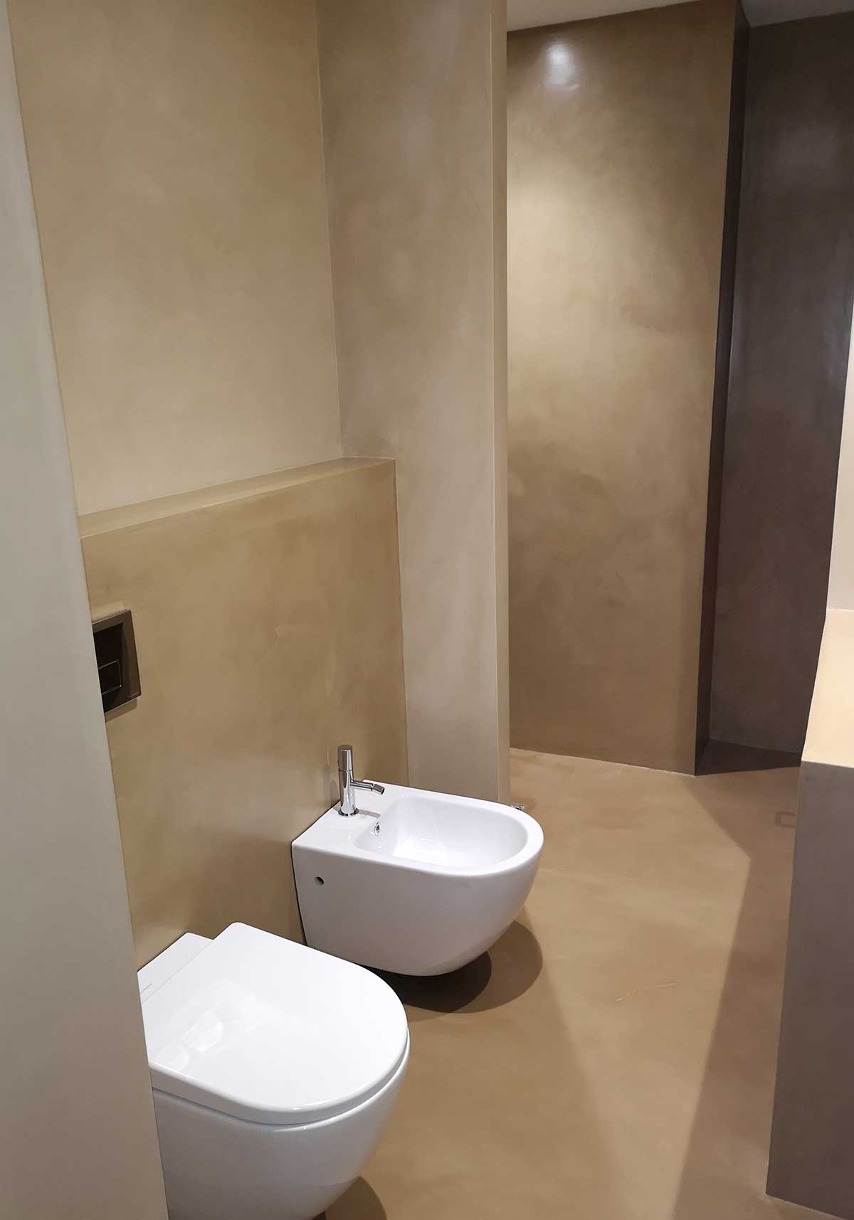 Walls, floors and shower tray in a bathroom made with brown microcement.
